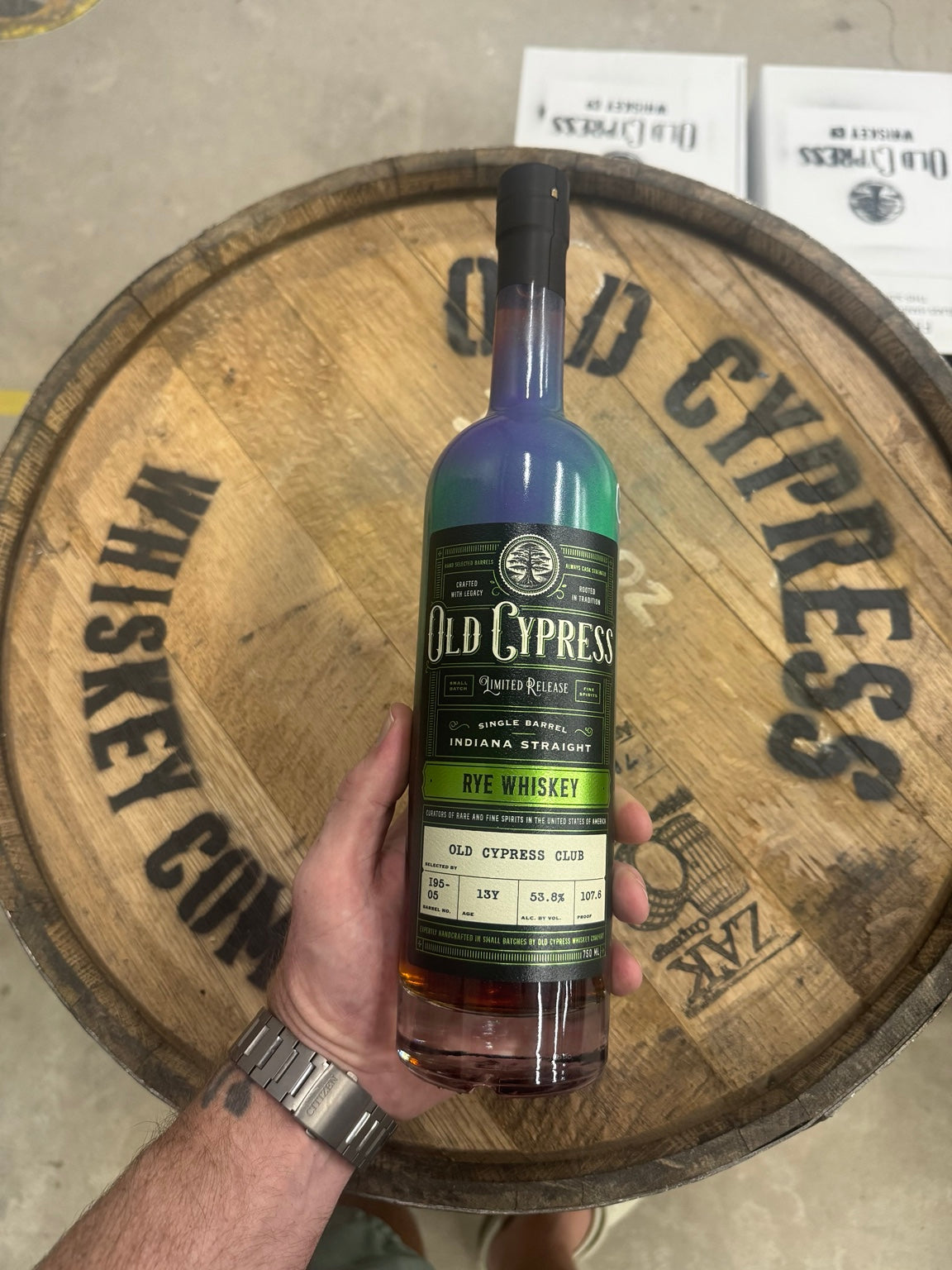 Old Cypress rye whiskey bottle in front of a barrel